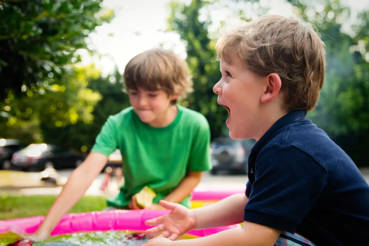 Two kids playing in a kiddy pool.