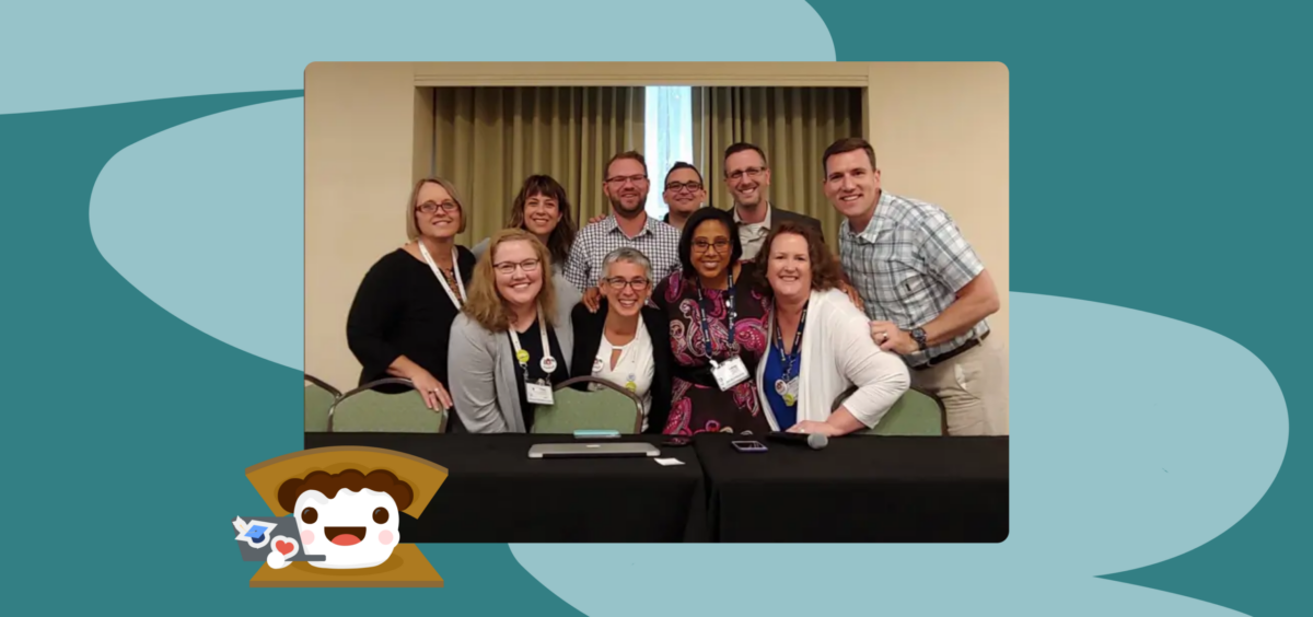 Group photo of conference attendees with Smore mascot on laptop in front.