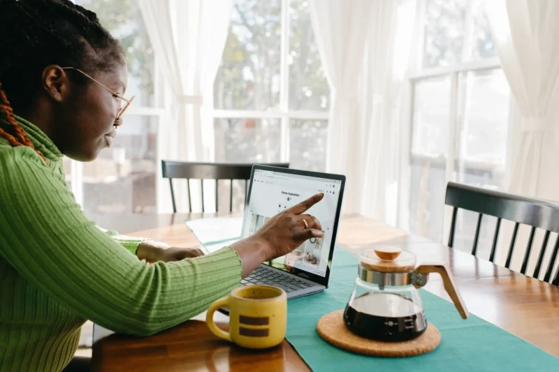 Woman drinking her morning coffee and using a laptop.